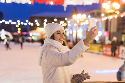 Man standing in illuminated park during winter at night