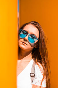 Portrait of beautiful woman standing against orange wall