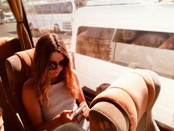 Young woman using mobile phone while traveling in bus