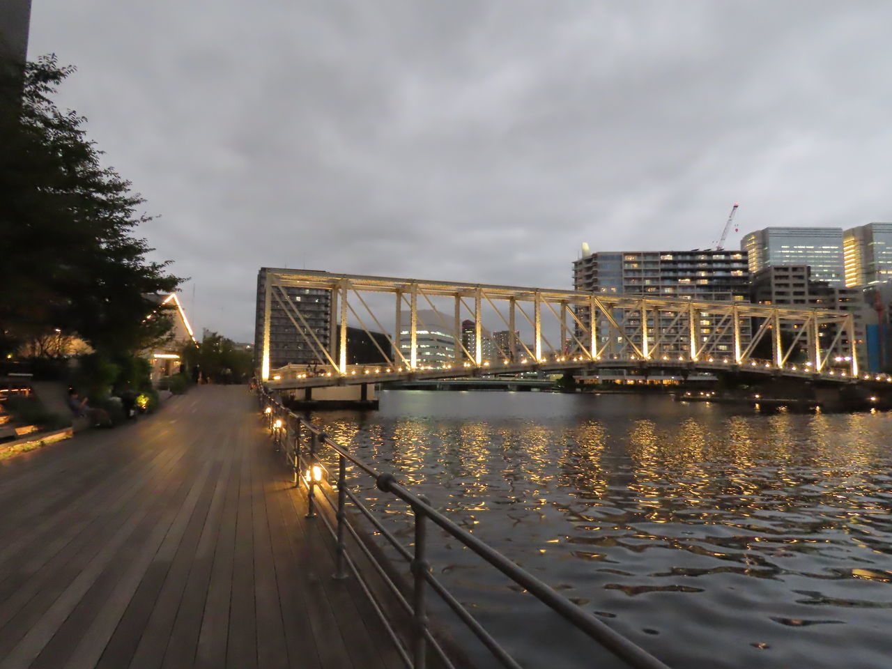 ILLUMINATED BRIDGE OVER RIVER IN CITY AGAINST SKY