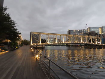 Bridge over illuminated city against sky at dusk