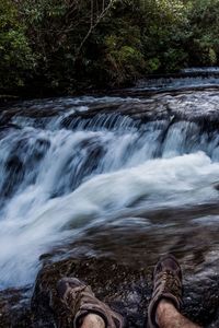 Low section of person by waterfall in forest