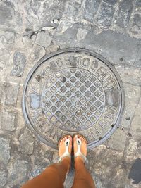 Low section of woman standing on manhole
