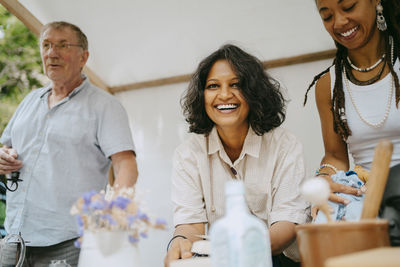 Portrait of happy woman with partners in stall at flea market