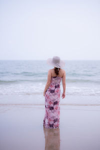 Woman standing at beach against sky