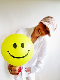 Close-up portrait of smiling woman holding smiley face ball