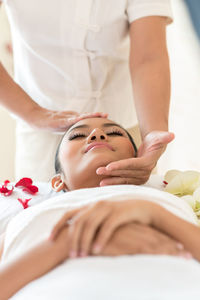 Therapist massaging while woman sleeping on bed at spa