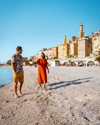 People on beach against clear blue sky