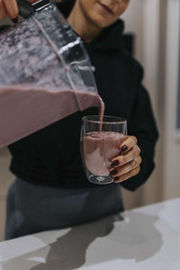 Woman pouring smoothie in glass