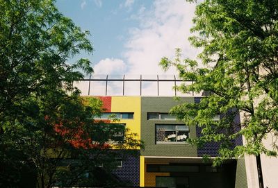 Low angle view of trees and building against sky