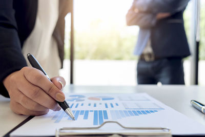 Midsection of businesswoman doing paperwork with businessman at desk in office