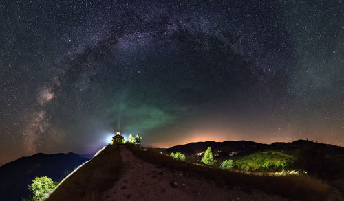 Distant view of illuminated chapel on mountain against star field