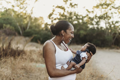 Portrait of young mother holdiing infant daughter in backlt field