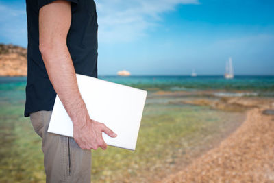 Midsection of man standing at beach against sky