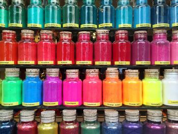 Full frame shot of colorful paint bottles arranged on shelf