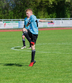 Full length of boy playing soccer on field