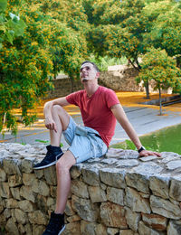 Portrait of man sitting on retaining wall