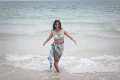 Side view of young woman standing at shore at beach