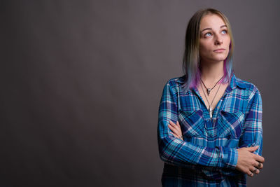 Portrait of beautiful young woman standing against black background