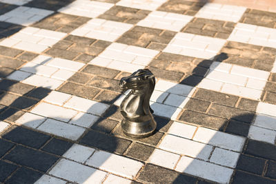 High angle view of chess pieces on tiled floor