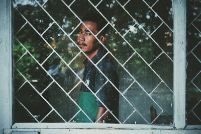 Portrait of young man seen through glass window