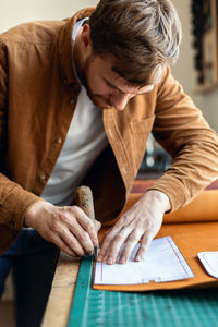 Midsection of man using mobile phone while sitting on table