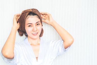 Portrait of smiling young woman against wall