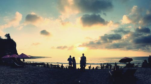 Silhouette people on beach against sky during sunset