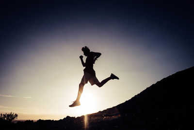 Silhouette man jumping at sunset
