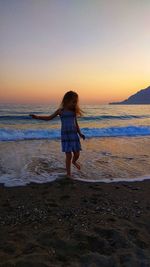 Rear view of man standing on beach during sunset