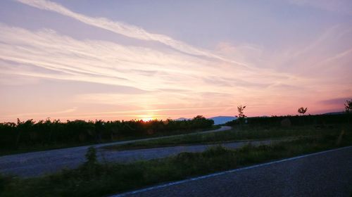 Road by silhouette landscape against sky during sunset