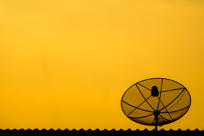 Silhouette of telephone pole against orange sky