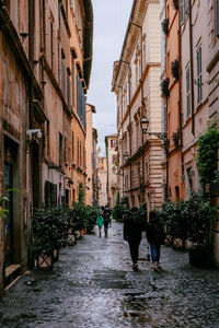 People walking in a small and narrow cobblestone street with traditional houses - rome, italy