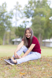 Young woman smiling while sitting on land