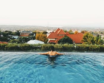 Man relaxing in swimming pool against clear sky