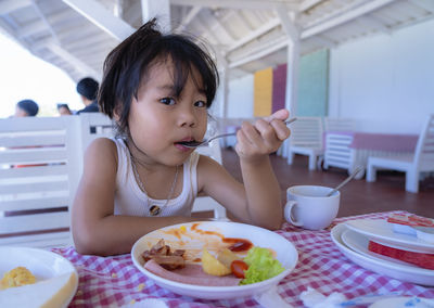 Portrait of child girl having food at the restaurant