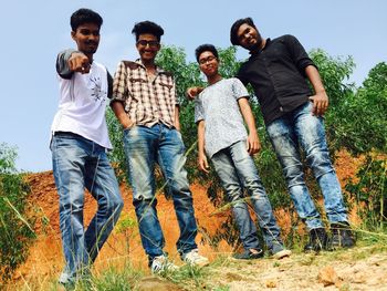 Full length of happy friends standing on field against sky