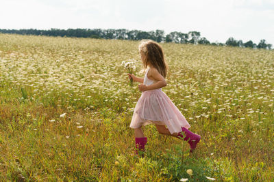 Little girl running in a flower field in the summer.