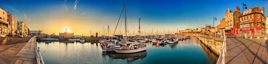 Boats moored in harbor against buildings in city