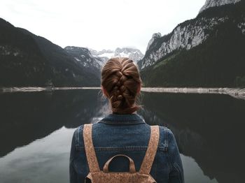 Rear view of woman standing against lake and mountains