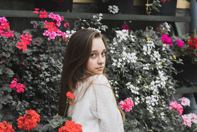 Portrait of young woman standing by flowering plants