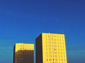 Low angle view of yellow building against blue sky