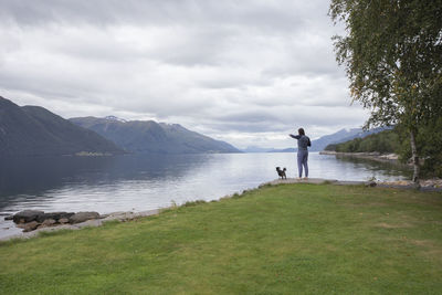 A man and his small dog looking across the fjord in norway