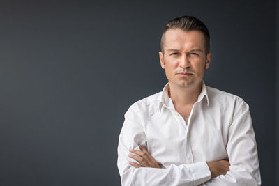 Portrait of man standing against gray background