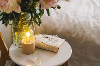 Open book with glasses, cup coffee and bouquet white pink peonies flowers. read and rest. cozy home