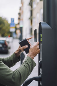 Hands of man doing mobile payment at charging station