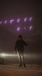 Full length of man standing on illuminated street at night