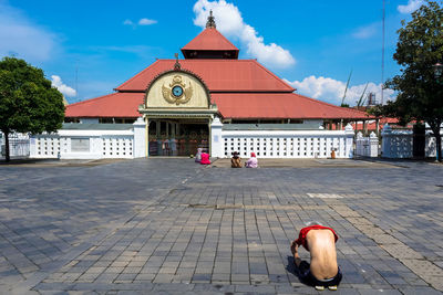 Rear view of man practicing yoga outside temple