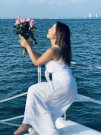 Side view of young woman photographing sea against sky