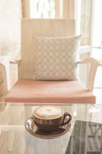 Coffee cup on table by chair in cafe